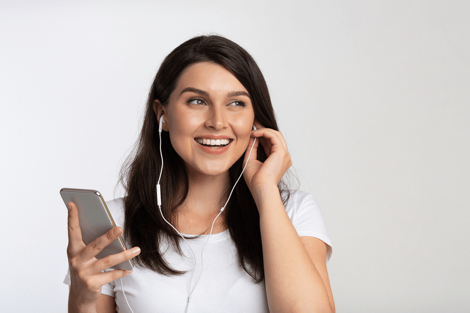Junge Frau mit dunklen Haaren, Headset und Smartphone in der Hand