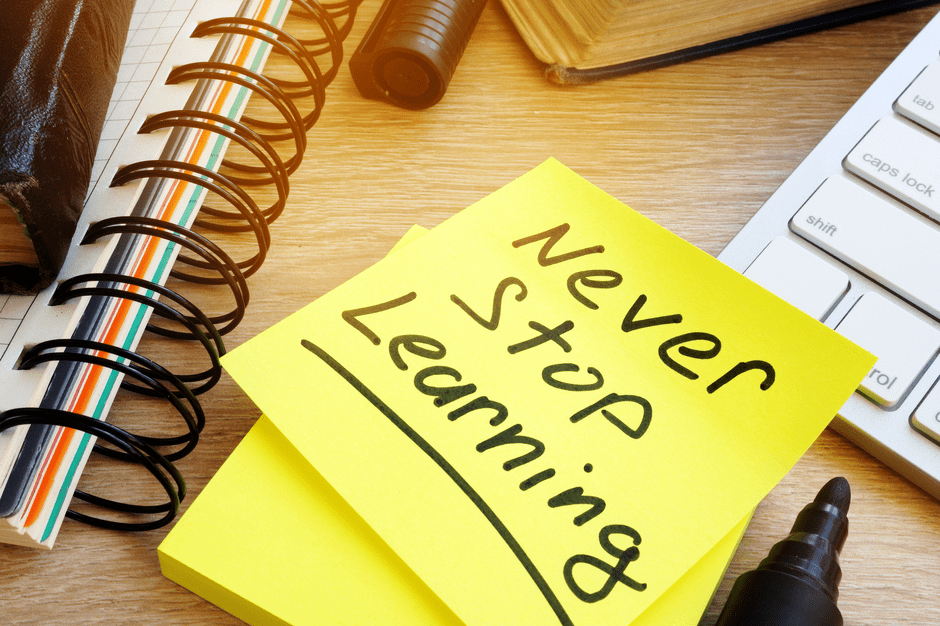 Gelbes post-it mit Text "Never stop Learning" zwischen Büro-Utensilien